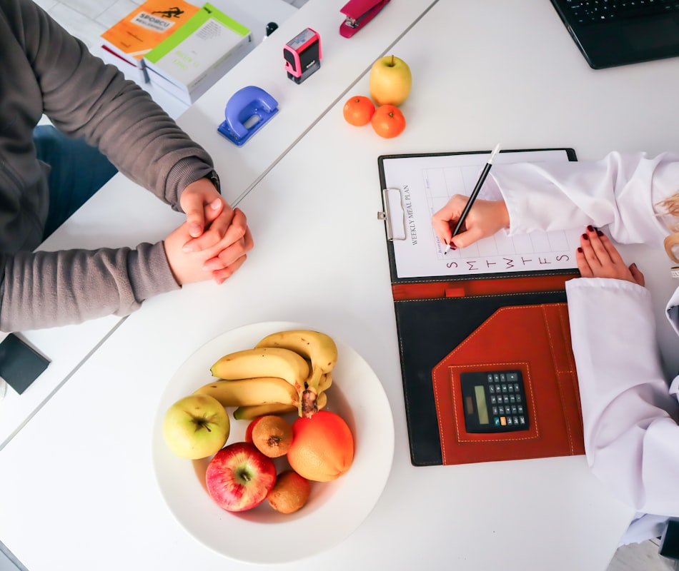 Professional nutrition consultant reviewing detailed dietary analysis with client charts and food journals